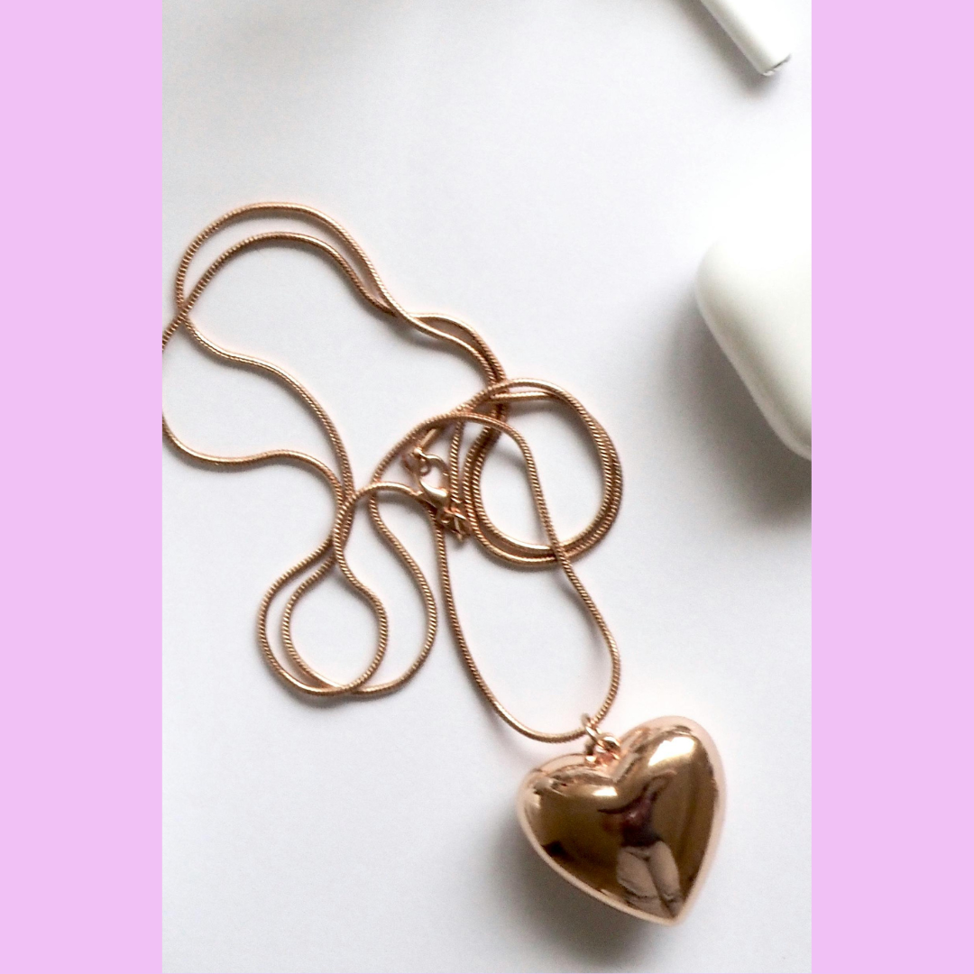 This image features a minimalist, elegant heart-shaped pendant in rose gold, suspended on a sleek, matching chain.