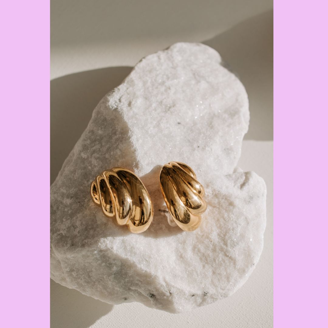 The image shows a pair of gold earrings with a textured, wavy design.